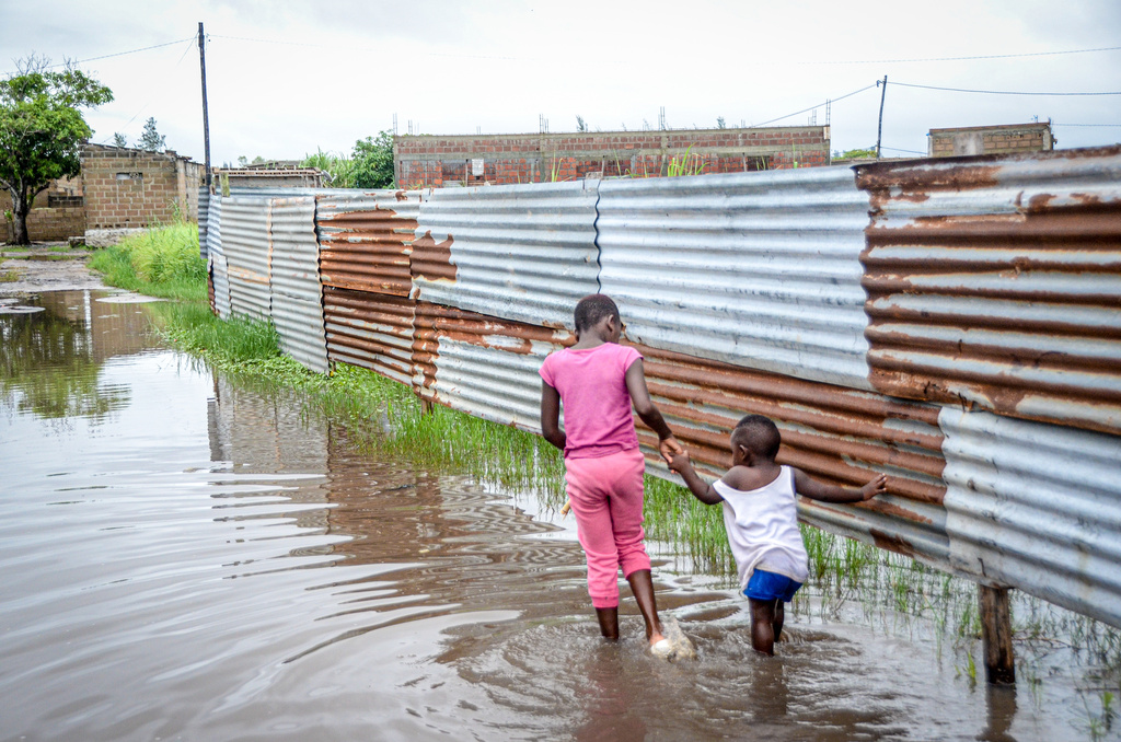 Children wade through floodwaters in a neighborhood in Maputo, Mozambique, on Friday, Jan. 16, 2026. (AP Photo/Carlos Uqueio)