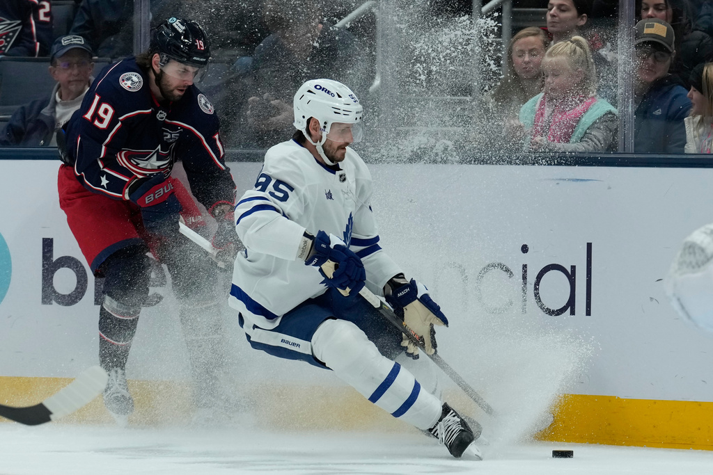 Columbus Blue Jackets center Adam Fantilli (19) and Toronto Maple Leafs defenseman Oliver Ekman-Larsson (95) battle for the puck in the first period of an NHL hockey game, Wednesday, Nov. 26, 2025, in Columbus. (AP Photo/Carolyn Kaster)