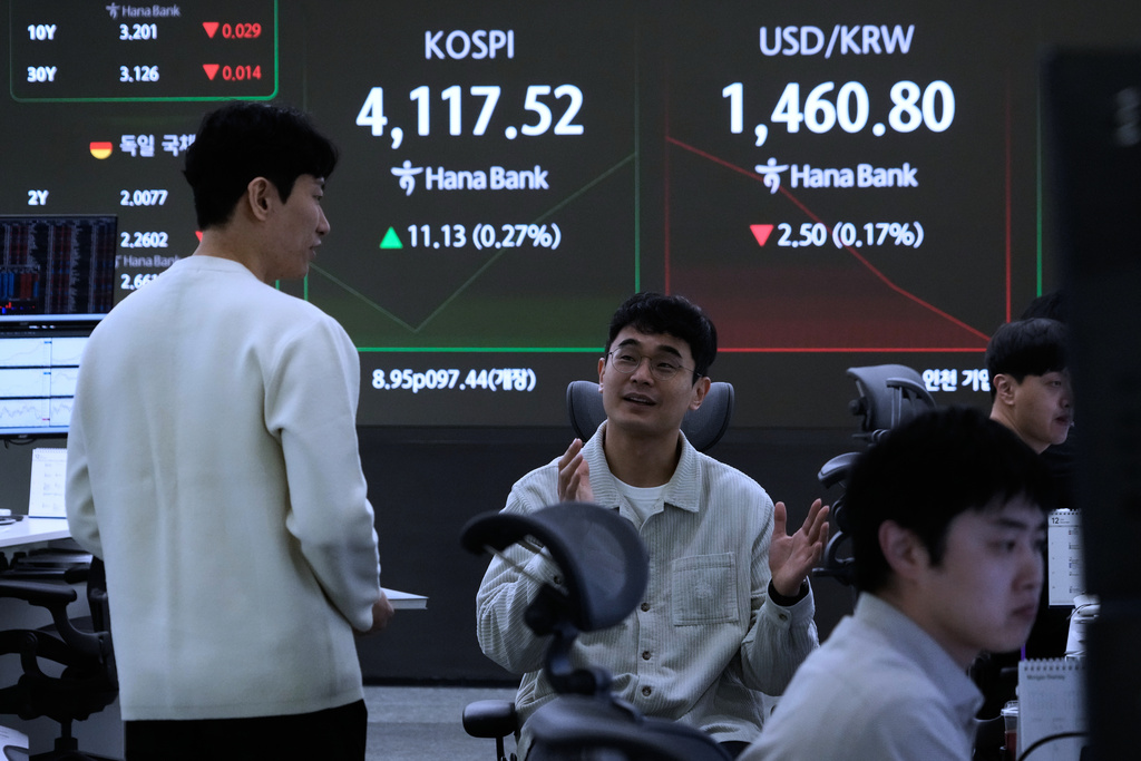 Currency traders work near a screen showing the Korea Composite Stock Price Index (KOSPI) and the foreign exchange rate between U.S. dollar and South Korean won, right, at the foreign exchange dealing room of the Hana Bank headquarters in Seoul, South Korea, Wednesday, Nov. 12, 2025. (AP Photo/Ahn Young-joon)