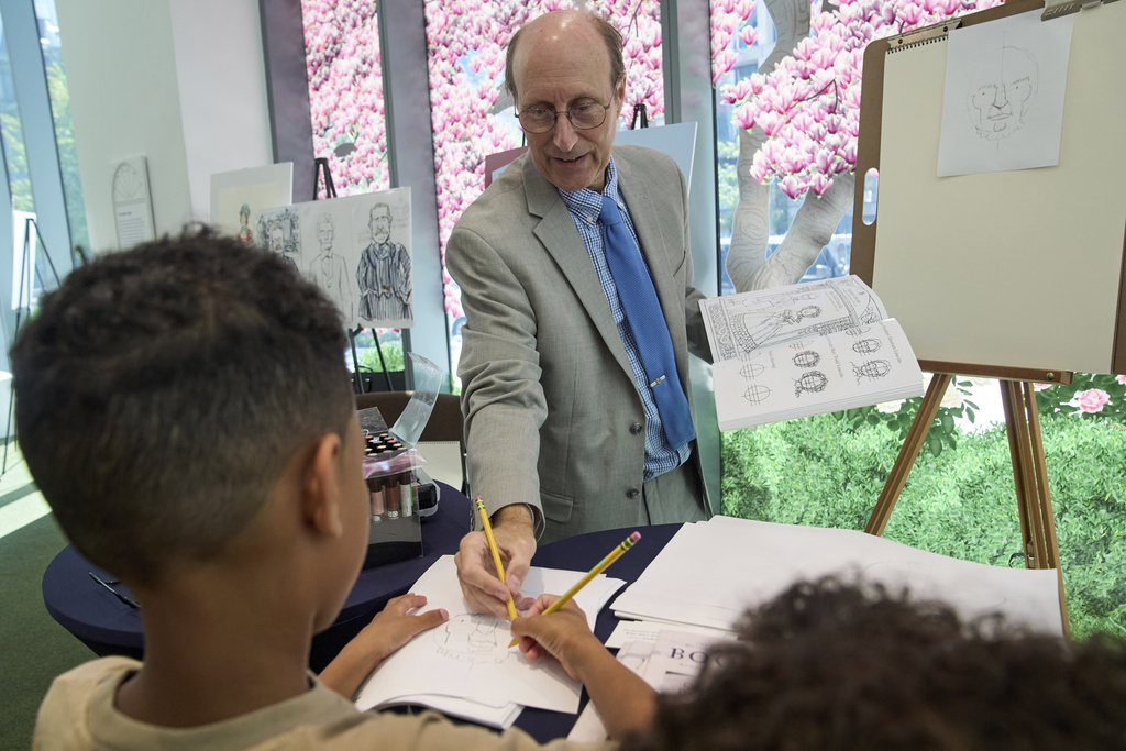 John Hutton, illustrator and professor of art history at Salem College, shows Aidan Santos, 8, of Long Island, N..Y., how to draw a picture of President Abraham Lincoln, Tuesday, Aug. 12, 2025, from his book, "How To Draw The Presidents and First Ladies," at The People's House, a museum in Washington. (AP Photo/Jacquelyn Martin)