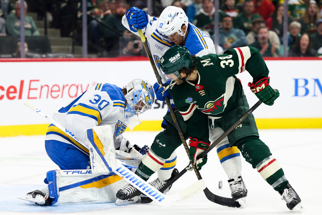 St. Louis Blues goaltender Joel Hofer (30) protects the net while Blues defenseman Cam Fowler (17) and Minnesota Wild right wing Ryan Hartman (38) battle during the first period of an NHL hockey game Sunday, March 1, 2026, in St. Paul, Minn. (AP Photo/Ellen Schmidt)