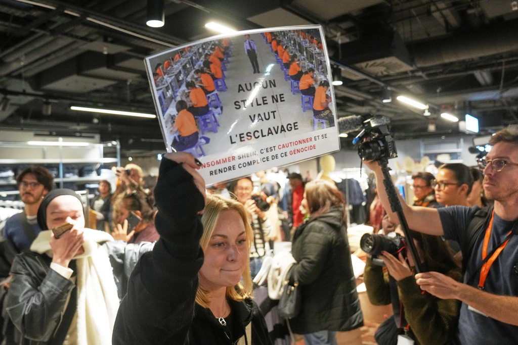 A protester holds a placard reading "No style worth slavery" in the BHV department store as fast fashion Shein opens its first physical store, Wednesday, Nov. 5, 2025 in Paris. (AP Photo/Thibault Camus)