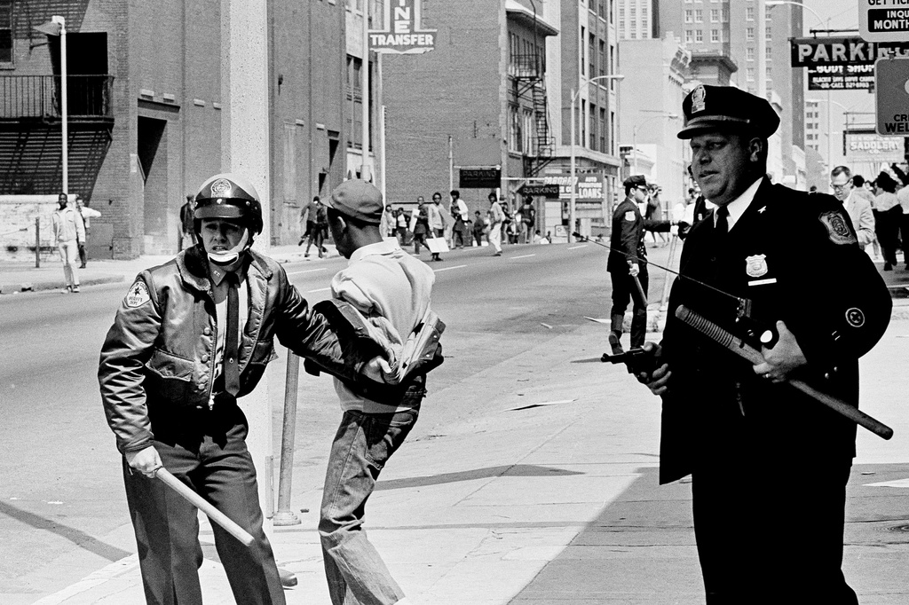 FILE- A policeman holds his revolver at the ready as he and another officer retreat with a looter in custody, during racial unrest in Memphis, Tenn., March 28, 1968. (AP Photo/Jack Thornell, File)