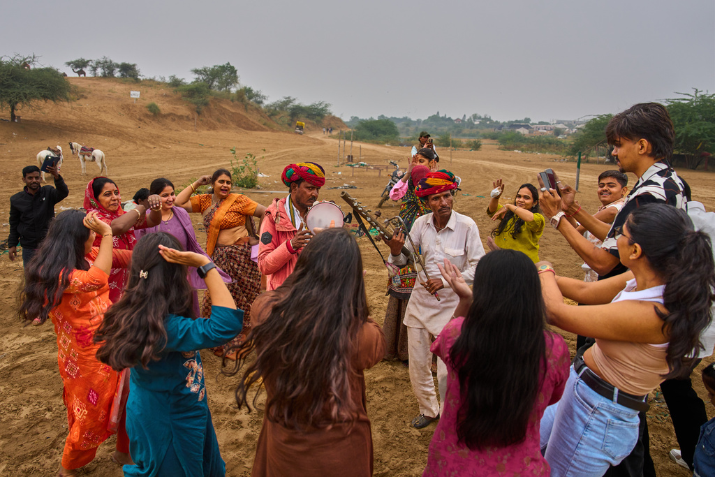 Tourists dance with locals during the annual cattle fair in Pushkar, in the western Indian state of Rajasthan, Monday, Oct. 27, 2025. (AP Photo/Rajesh Kumar Singh)