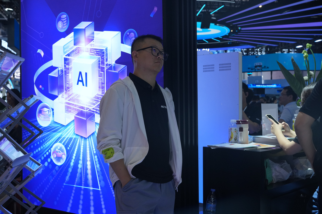 A visitor stands near a display about AI during the World AI Conference in Shanghai, China on July 17, 2026. (AP Photo/Ng Han Guan)