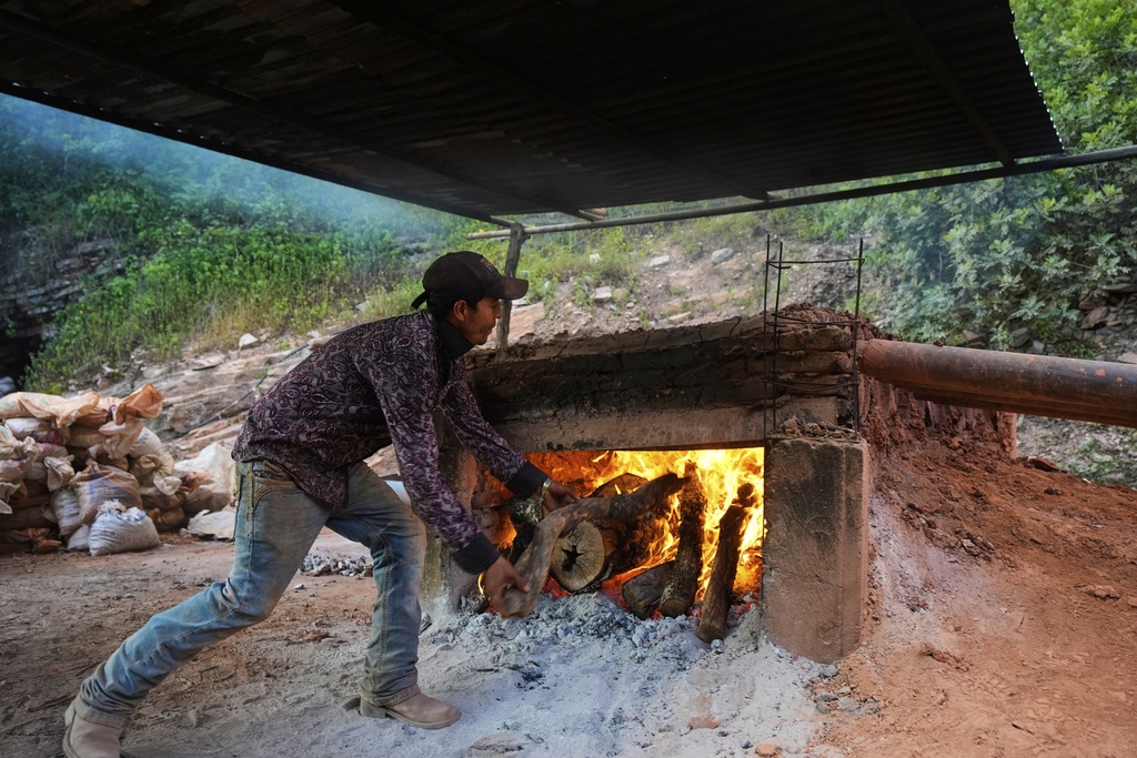 Carlos Raul Martinez feeds the fire in the artisanal furnace where mercury ore is cooked in San Joaquin, Mexico, Tuesday, Aug. 19, 2025. (AP Photo/Fernando Llano)