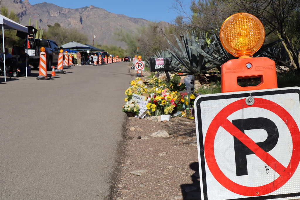 "No parking" signs stand along one side of the road that Nancy Guthrie lives on in Tucson, Ariz., Sunday, Feb. 22, 2026, while canopies and vehicles of people covering the investigation line the other side. (AP Photo/Felicia Fonseca)