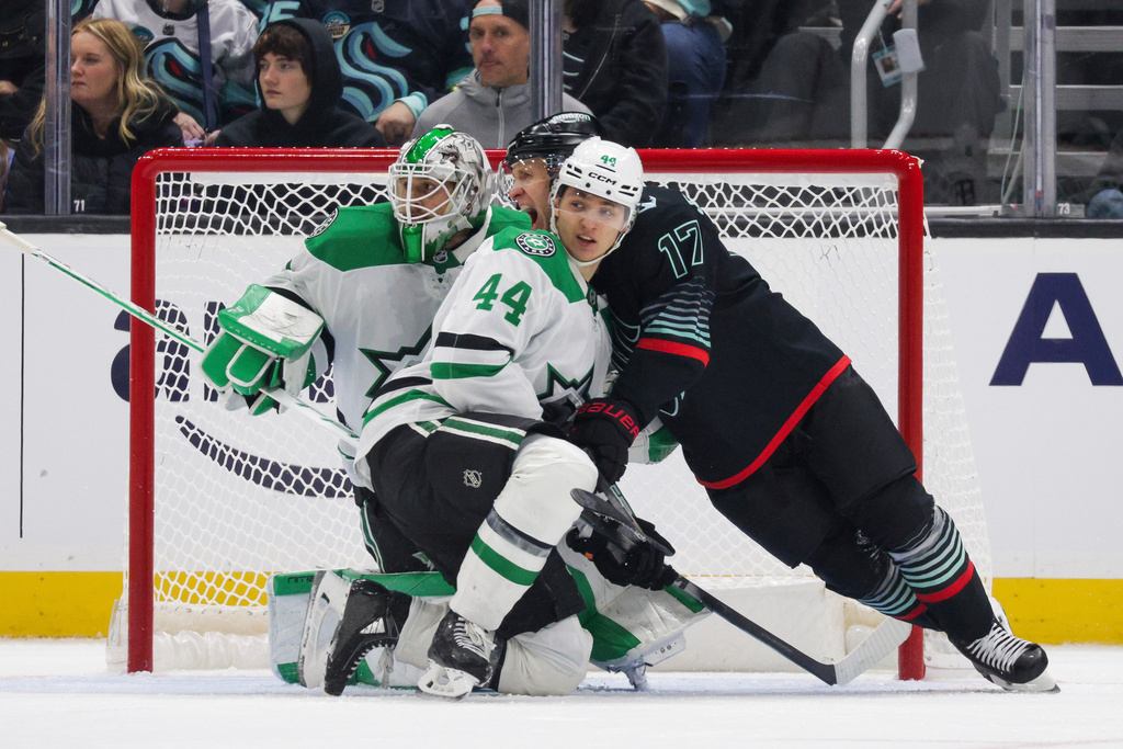 Seattle Kraken left wing Jaden Schwartz (17) fights for position as Dallas Stars defenseman Vladislav Kolyachonok (44) and goalie Casey DeSmith defend during the second period of an NHL hockey game Wednesday, Nov. 26, 2025, in Seattle. (AP Photo/Jason Redmond)