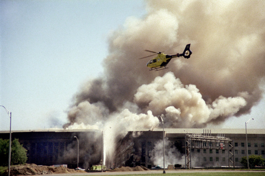 FILE - A helicopter flies over the Pentagon as smoke billows over the building in Washington, Sept. 11, 2001. (AP Photo/Heesoon Yim, File)