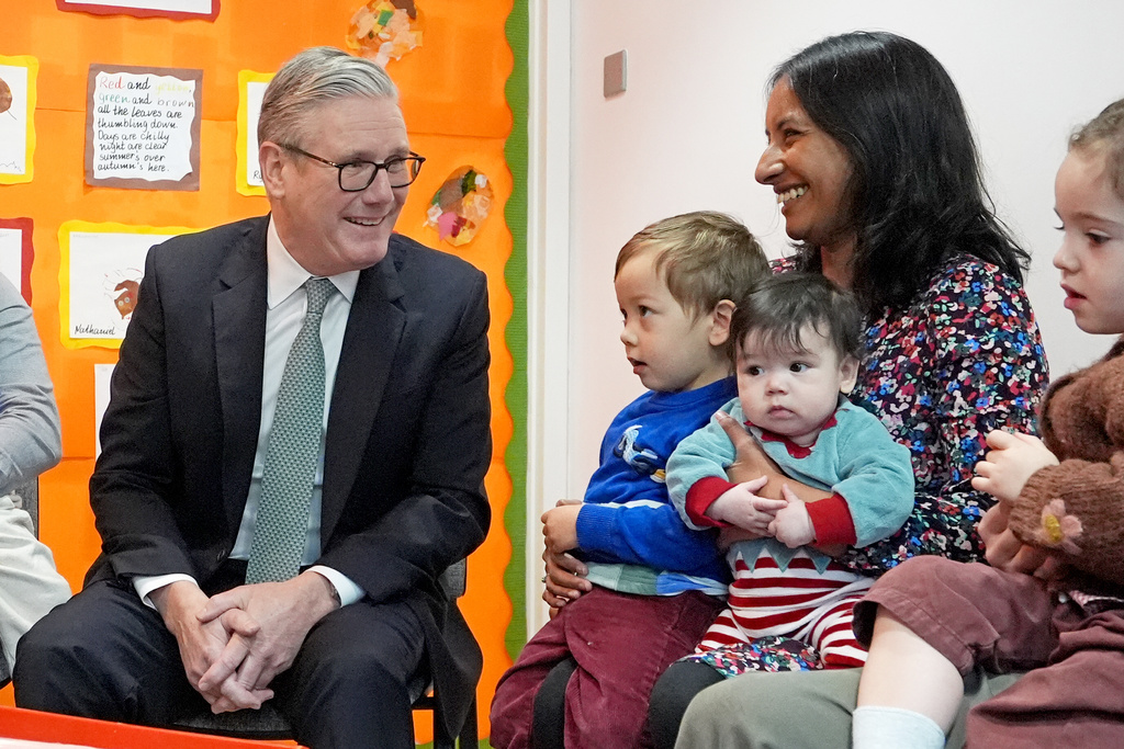 Britain's Prime Minister Keir Starmer, left, speaks with parents and children during his visit to a nursery, in central London, Monday, Dec. 1, 2025. (Gareth Fuller/Pool Photo via AP)