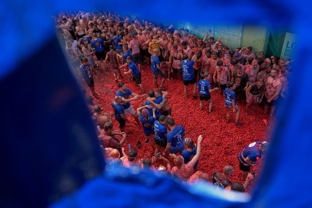 Revelers throw tomatoes at each other during the annual "Tomatina" tomato fight fiesta, in the village of Bunol near Valencia, Spain, Wednesday, Aug. 26, 2026. (AP Photo/Alberto Saiz)