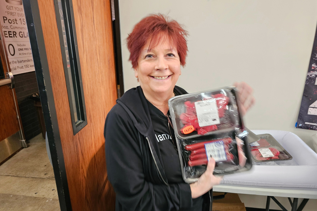 Andrea "Mama" Avaloz holds up the package of fajita meat, beef sticks and pork chops that she won in a meat raffle April 10, 2026, at American Legion Post 150 in Waconia, Minn. (AP Photo/Steve Karnowski)