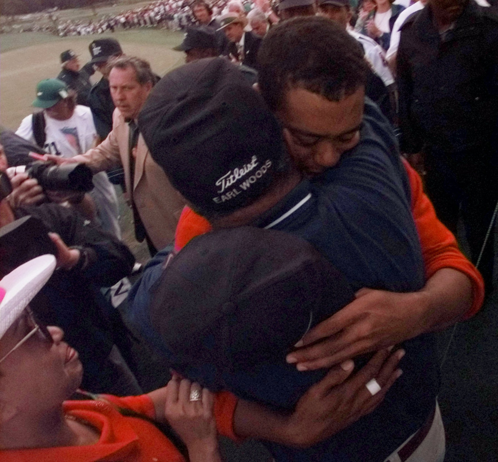 FILE - Tiger Woods hugs his his father Earl, as his mother, Kultida, looks on, after winning the 1997 Masters with a record-breaking 18-under-par at the Augusta National Golf Club, in Augusta, Ga., Sunday, April 13, 1997. (AP Photo/Dave Martin )