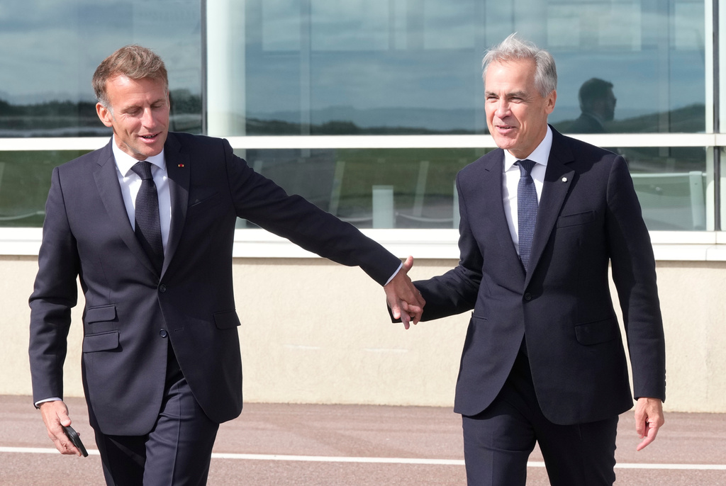 French President Emmanuel Macron, left, leads Canadian Prime Minister Mark Carney to his plane after the leaders delivered remarks in Saint-Pierre, Saint-Pierre-et-Miquelon, Sunday, Sept.20, 2026. (Adrian Wyld/The Canadian Press via AP)