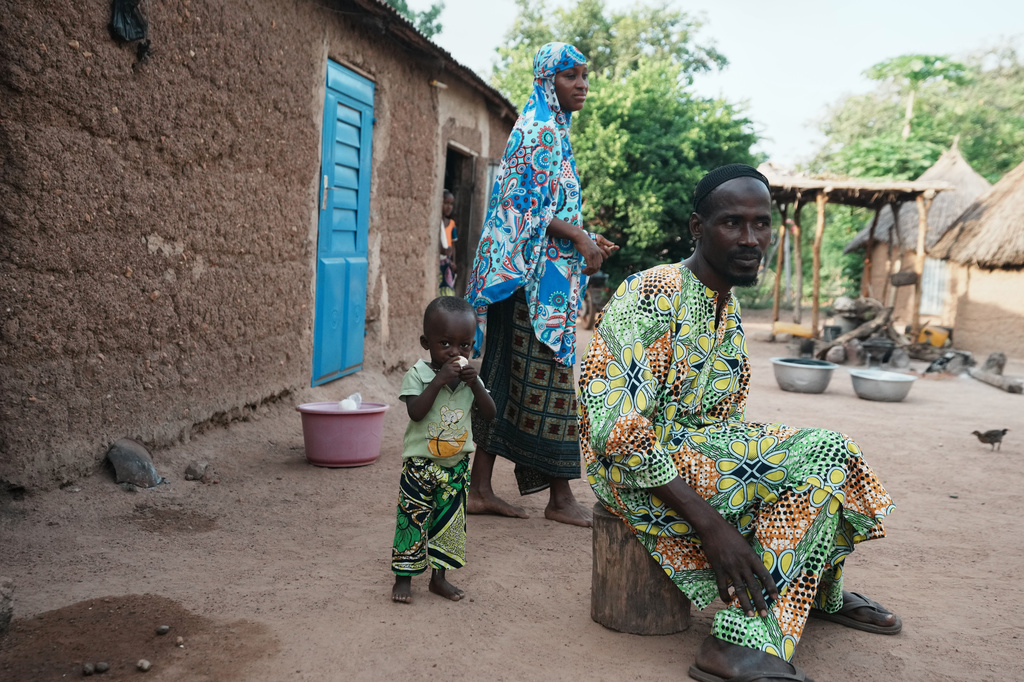 Sabi Bera Zakari, right, his wife Aboudou Salamatou, center, and their child Oumarou Zakari who suffers from stunted growth, stand outside their home in N'dali, northern Benin, Sunday, May 17, 2026. (AP Photo/Sunday Alamba)