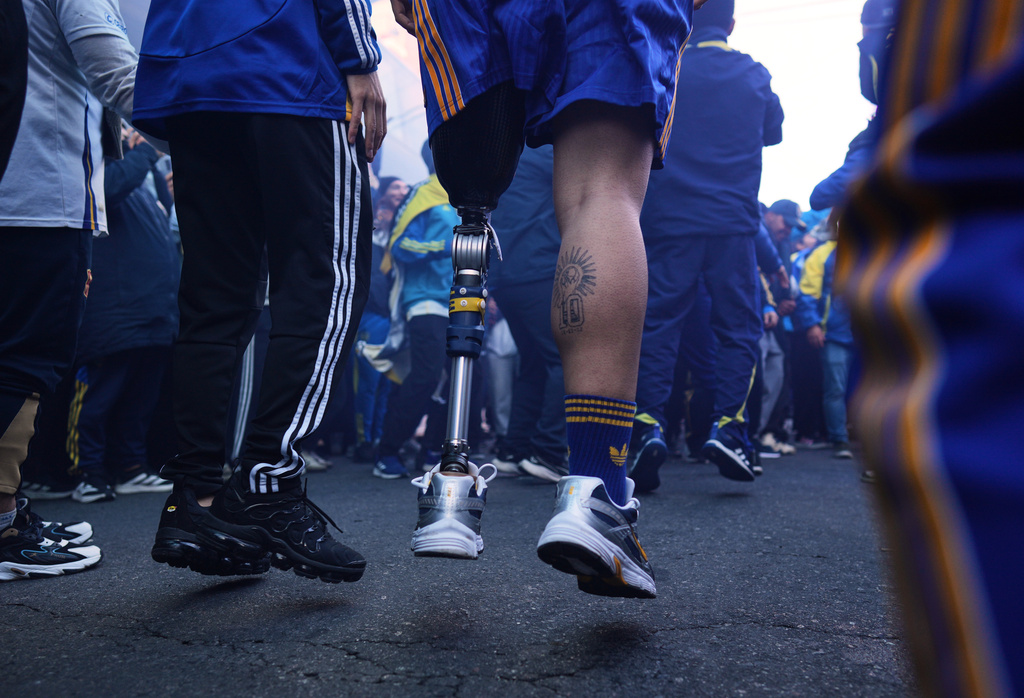 Ignacio Calle jumps with his prosthetic leg while singing Boca Juniors chants before entering the stadium for an Argentina league soccer match in Buenos Aires, Argentina, Saturday, May 9, 2026. (AP Photo/Rodrigo Abd)
