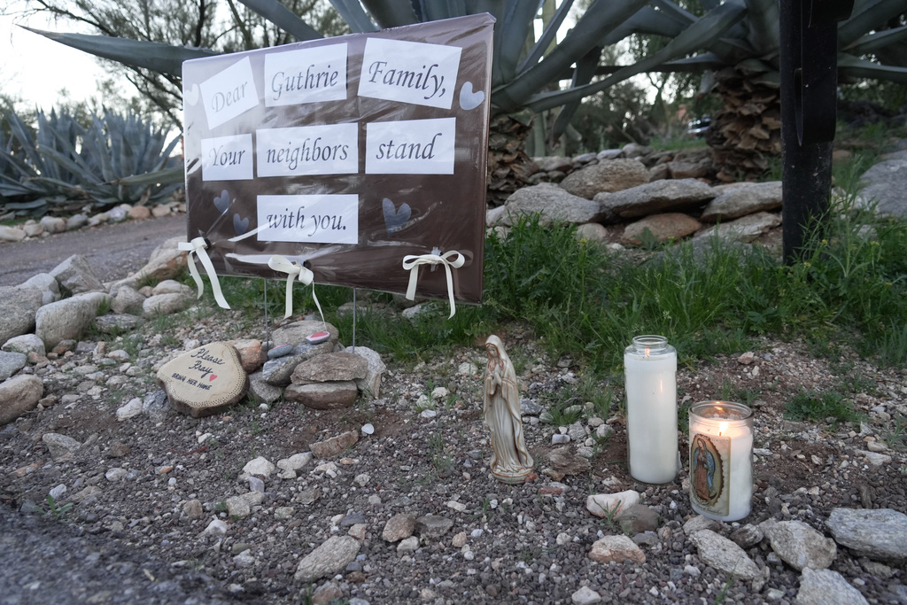Lit candles next to a sign from neighbors supporting the Guthrie family outside of Nancy Guthrie’s house in the early morning hours of Sunday, Feb. 8, 2026 in Tucson, Ariz. (AP Photo/Ty ONeil)