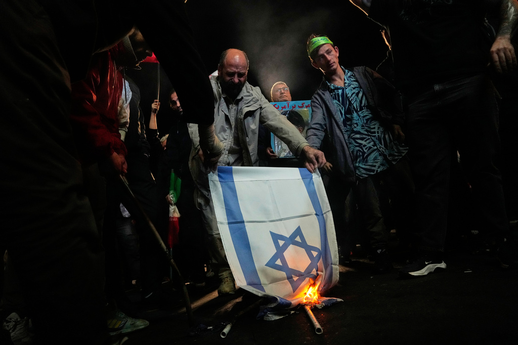 Iranian pro-government demonstrators burn an Israeli flag during a gathering after the announcement of a two-week ceasefire in the war with the Unites States and Israel, at the Enqelab-e-Eslami, or Islamic Revolution, Square in Tehran, Iran, Wednesday, April 8, 2026. (AP Photo/Vahid Salemi)