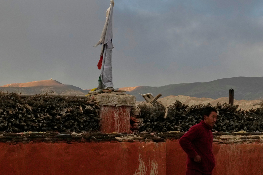 A surveillance camera in China is seen atop a hill in the background, as a Buddhist monk stands at a monastery, in the ancient ethnic Tibetan city of Mustang, Nepal, April 18, 2025. (AP Photo/Niranjan Shrestha)