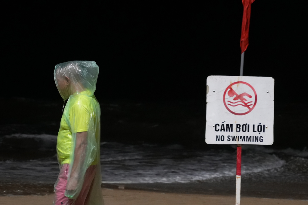 A man walkspast a "No Swimming" sign due to Typhoon Kalmaegi on a beach in Khanh Hoa, Vietnam, Thursday, Nov. 6, 2025. (AP Photo/Hau Dinh)