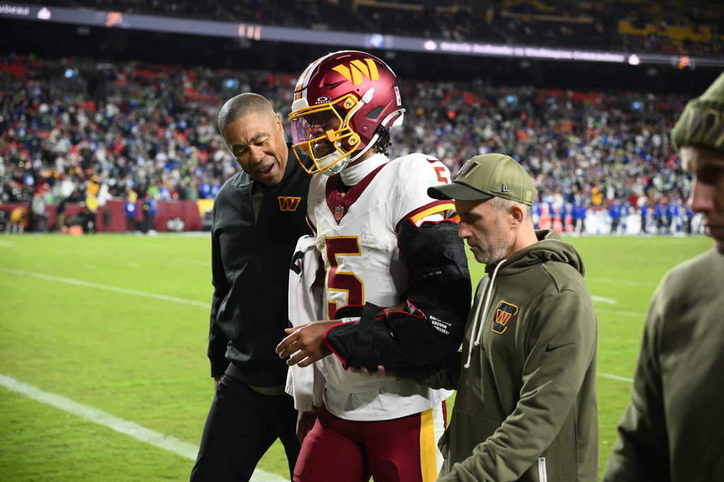 Washington Commanders quarterback Jayden Daniels (5) is helped off the field after he injuring his arm during a play in the second half of an NFL football game, Sunday, Nov. 2, 2025, in Landover, Md. (AP Photo/Nick Wass)