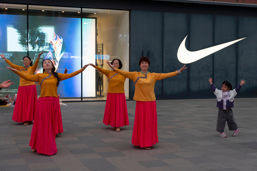 A child mimics women dancing in front of a Nike store along Wangfujing shopping street in Beijing, Wednesday, May 6, 2026. (AP Photo/Ng Han Guan)