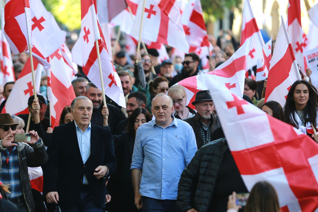 Paata Burchuladze, opera singer and one of the organizers of the rally, center left, and former Chief Prosecutor of Georgia Murtaz Zodelavaother, center, march with other opposition supporters carrying Georgian national flags in the city center of Tbilisi, Georgia, on Saturday, Oct. 4, 2025, boycotting the municipal elections and calling for the release of political opponents. (AP Photo/Zurab Tsertsvadze)