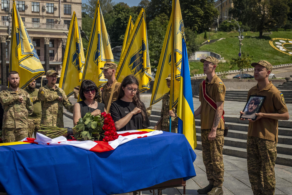 Relatives and soldiers of the Azov Regiment pay last respect near the coffin of their comrade, Georgian volunteer Mykhailo Kovaliv, during a farewell ceremony on Independence Square in Kyiv, Ukraine, Saturday, Aug. 9, 2025. (AP Photo/Dan Bashakov)