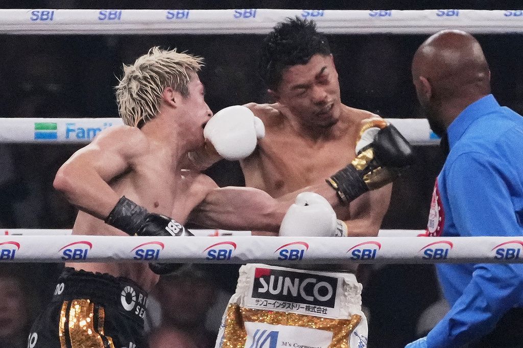Naoya Inoue of Japan, left, punches Junto Nakatani of Japan during the tenth round of a boxing match for the WBA, WBC, IBF and WBO super bantamweight world title in Tokyo, Saturday, May 2, 2026. (AP Photo/Hiro Komae)