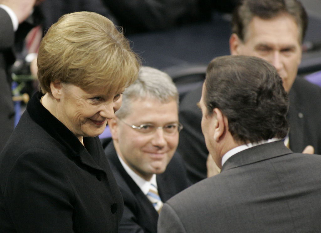 FILE - Newly elected German chancellor Angela Merkel, left, is congratulated by her predecessor Gerhard Schroeder, right, as lawmakers Norbert Roettgen and Michael Glos, background right, look on after her election in the parliament in Berlin, on Nov. 22, 2005. (AP Photo/Fritz Reiss, File)