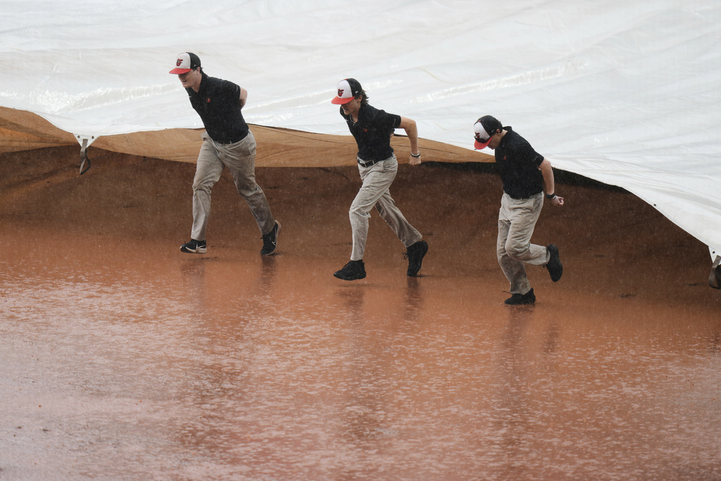 Members of the grounds crew place a tarp over the infield during a rain delay in the sixth inning of a baseball game between the Baltimore Orioles and the Seattle Mariners, Thursday, Aug. 14, 2025, in Baltimore. (AP Photo/Stephanie Scarbrough)