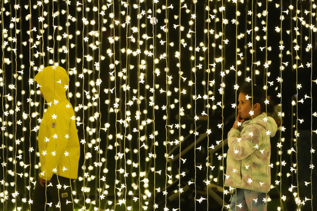 People walk through the San Francisco Botanical Garden's Winter Cathedral exhibit for Lightscape at Golden Gate Park in San Francisco, Wednesday, Dec. 17, 2025. (AP Photo/Jeff Chiu)