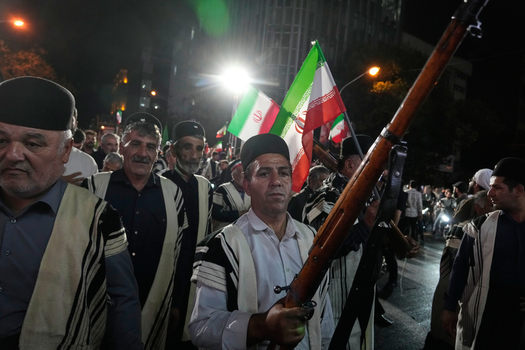 Bakhtiari nomads, wearing traditional dress, chant slogans as one of them holds a gun during a pro-government gathering near the residence where former Iranian Supreme Leader Ayatollah Ali Khamenei was killed in U.S. and Israeli strikes on Feb. 28, in Tehran, Iran, Monday, May 18, 2026. (AP Photo/Vahid Salemi)