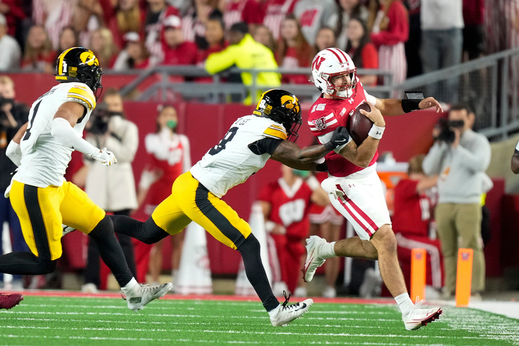 Wisconsin quarterback Hunter Simmons, right, scrambles against Iowa defensive back Deshaun Lee (8) during the second half of an NCAA college football game Saturday, Oct. 11, 2025, in Madison, Wis. (AP Photo/Andy Manis)