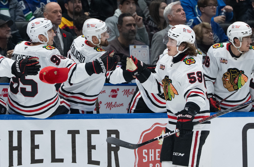 Chicago Blackhawks' Tyler Bertuzzi (59) celebrates his goal against the Vancouver Canucks with his teammates as a hat flies onto the ice during the third period of an NHL hockey game in Vancouver, British Columbia, Wednesday, Nov. 5, 2025. (Ethan Cairns/The Canadian Press via AP)