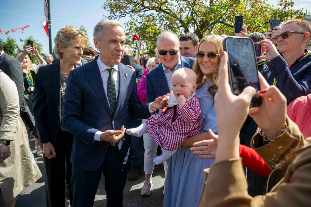Canadian Prime Minister Mark Carney, front left, has a picture taken with Lily Meskil, 9 months and her grandfather Ger Basquel and mother Rachel Basquel, during a visit to Aughagower, Ireland, Sunday, June 14, 2026. (Andrew Downes/PA via AP)