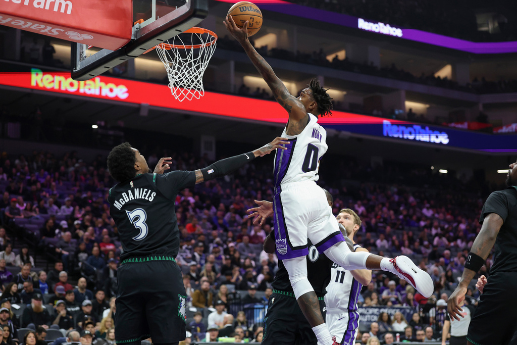 Sacramento Kings guard Malik Monk (0) goes up for a layup surrounded by Minnesota Timberwolves defenders during the first half of an NBA basketball game Sunday, Nov. 9, 2025, in Sacramento, Calif. (AP Photo/Sara Nevis)