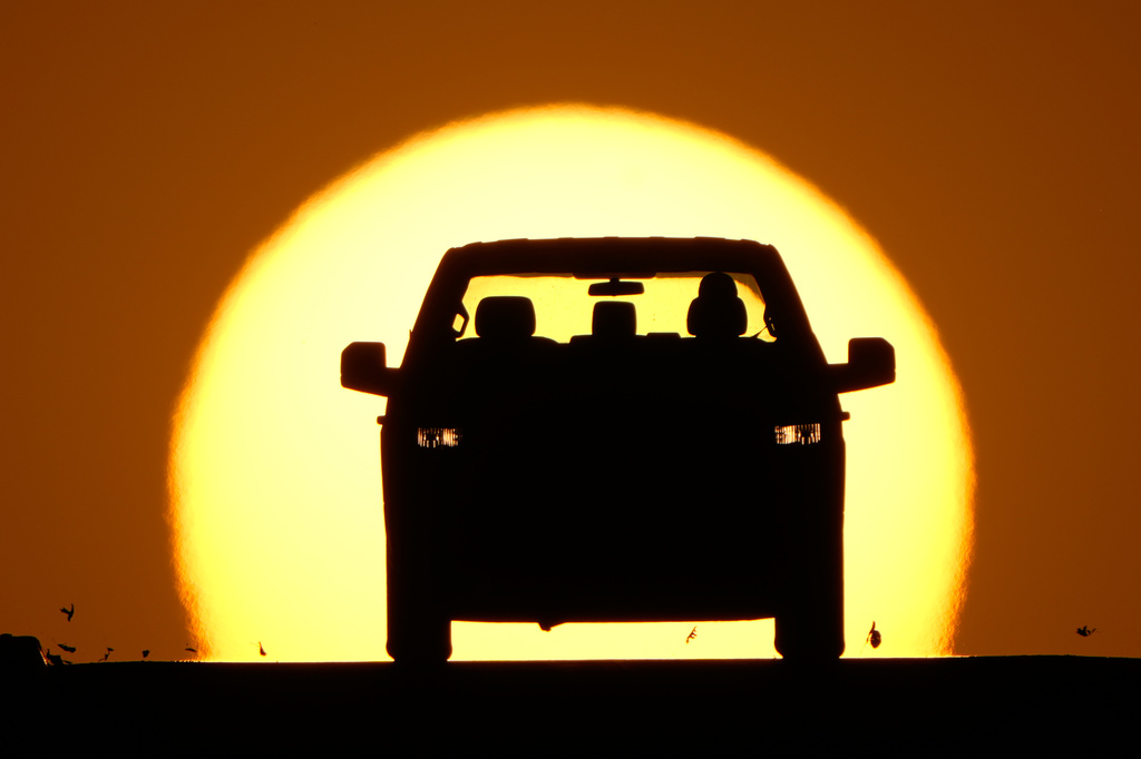 FILE - A motorist is silhouetted by the setting sun March 26, 2026, in Lenexa, Kan. (AP Photo/Charlie Riedel)