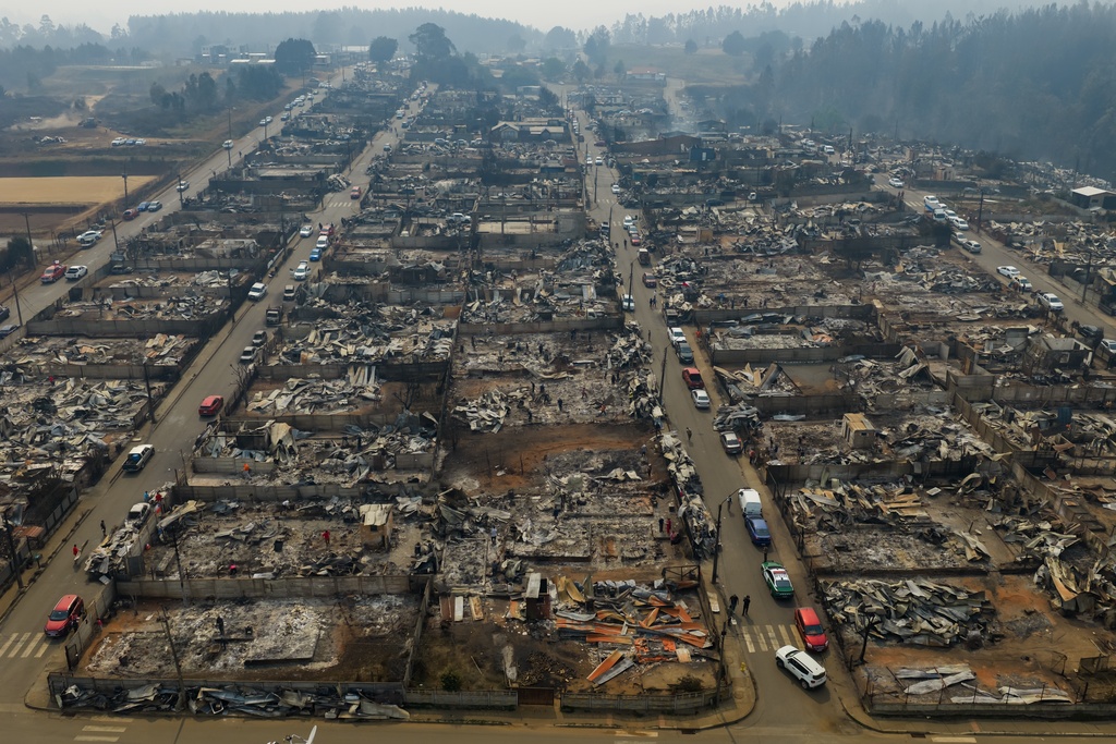 FILE - Cars line the streets near wildfire-burned homes in Tome, Chile, Jan. 19, 2026. (AP Photo/Javier Torres, FIle)