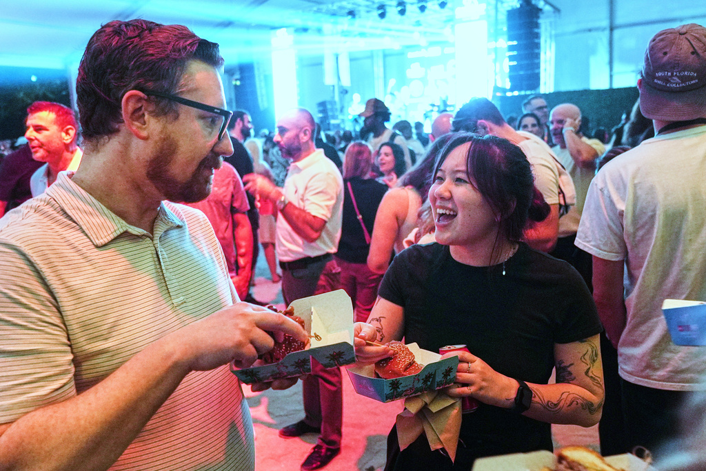 A couple enjoys the Burger Bash at the South Beach Wine and Food Festival Friday, Feb. 20, 2026, in Miami Beach, Fla. (AP Photo/Marta Lavandier)