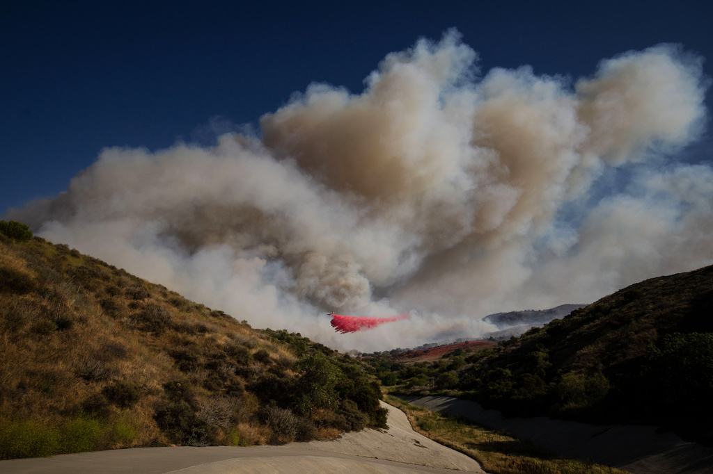 FILE - An air tanker drops fire retardant on the Sandy Fire on May 18, 2026, in Simi Valley, Calif. (AP Photo/Ethan Swope, File)