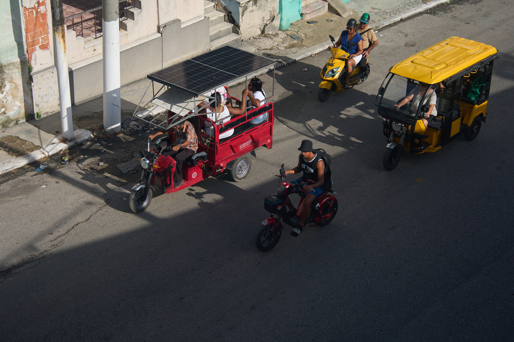 People ride in electric tricycles in Havana, Cuba, Friday, July 10, 2026. (AP Photo/Ramon Espinosa)