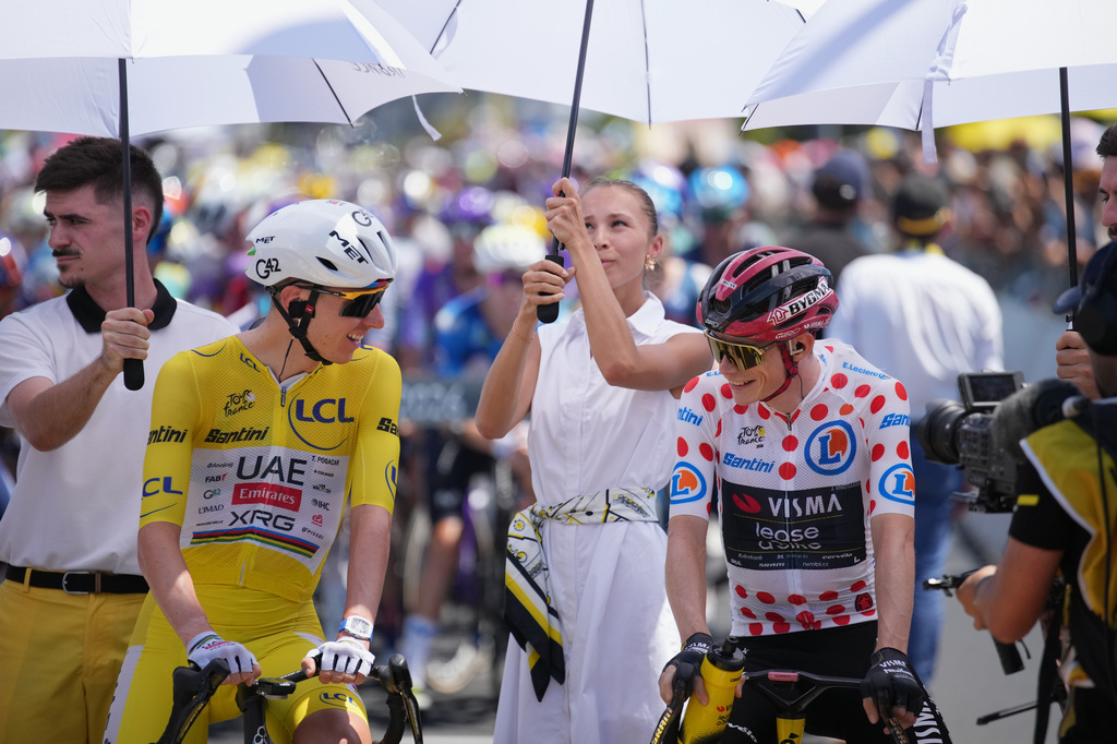 Slovenia's Tadej Pogacar, wearing the overall leader's yellow jersey, and Denmark's Jonas Vingegaard, wearing the best climber's dotted jersey, are shielded from the sun ahead of the start of the ninth stage of the Tour de France cycling race with start in Malemort and finish in Ussel, France, Sunday, July 12, 2026. (AP Photo/Mosa'ab Elshamy)