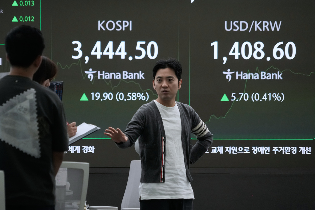 Currency traders work near a screen showing the Korea Composite Stock Price Index (KOSPI) and the foreign exchange rate between U.S. dollar and South Korean won, top right, at the foreign exchange dealing room of the Hana Bank headquarters in Seoul, South Korea, Wednesday, Oct. 1, 2025. (AP Photo/Ahn Young-joon)