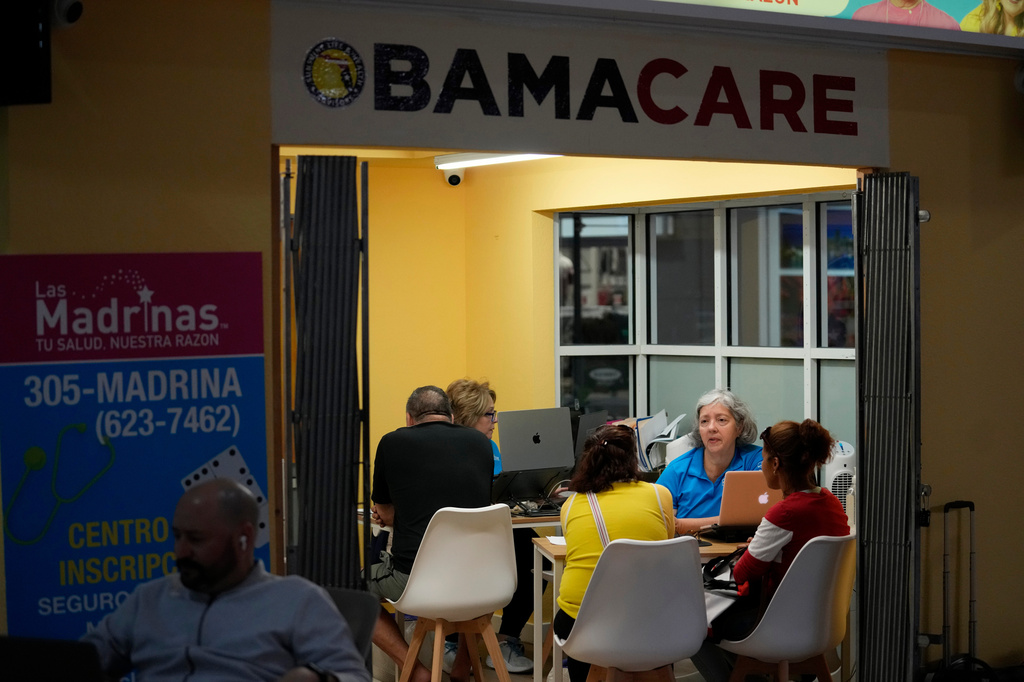 FILE - Insurance agent Maria Collado, center right, works with clients at a shopping mall kiosk run by Las Madrinas de los Seguros, Spanish for "The Godmothers of Insurance," at a shopping center in Miami, Dec. 5, 2023. (AP Photo/Rebecca Blackwell, File)