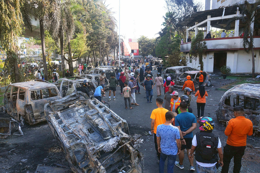 People inspect the wreckages of cars burned in a protest against lavish allowances given to parliament members in Makassar, South Sulawesi, Indonesia, Saturday, Aug. 30, 2025. (AP Photo/ Masyudi Firmansyah)