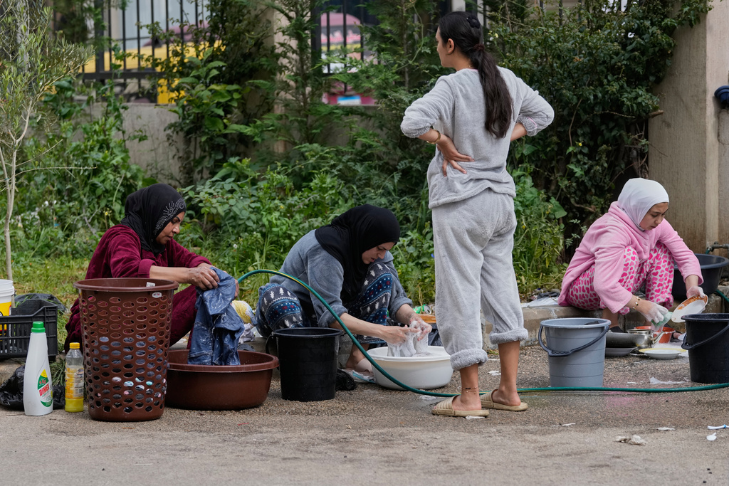 Displaced women who fled Israeli strikes from south Lebanon, wash their laundries at a school playground turned into a shelter, in the southern port city of Sidon, Lebanon, Saturday, March 14, 2026. (AP Photo/Mohammed Zaatari)