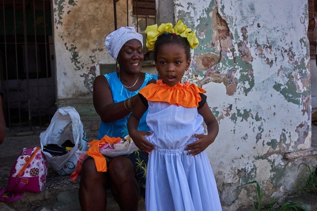A woman helps a young dancer with her costume for an outdoor performance led by choreographer Juan Miguel Mas, in a neighborhood of Havana, Cuba, Saturday, May 9, 2026. (AP Photo/Ramon Espinosa)