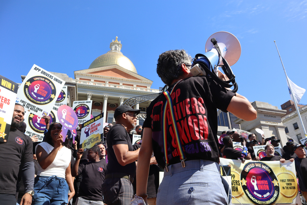 An organizer with the App Drivers Union speaks through a megaphone during a during a rally outside the Massachusetts State House after the App Drivers Union announced it had become the first certified union of rideshare drivers in the nation, on Tuesday, May 26, 2026, in Boston. (AP Photo/Leah Willingham)