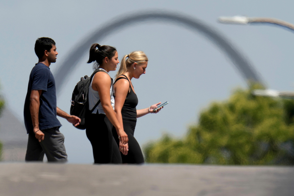 FILE - The Gateway Arch is seen through heatwaves in the distance as pedestrians use a crosswalk, July 23, 2025, in St. Louis. (AP Photo/Jeff Roberson, File)